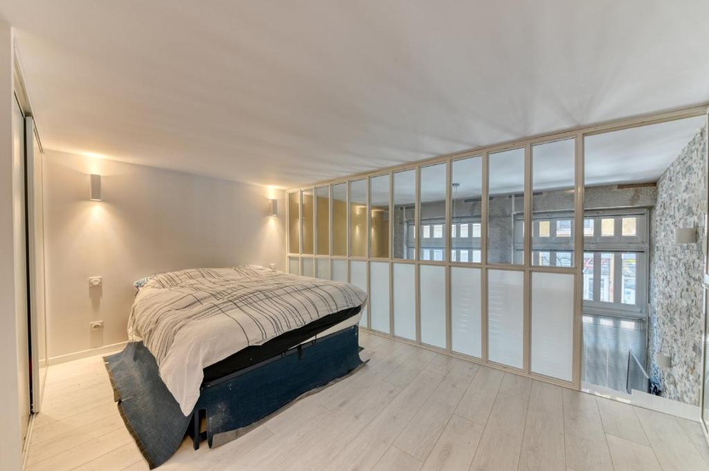 a bedroom with a bed in a room with windows at GuestReady - Stonewall Mezzanine in Brotteaux in Lyon