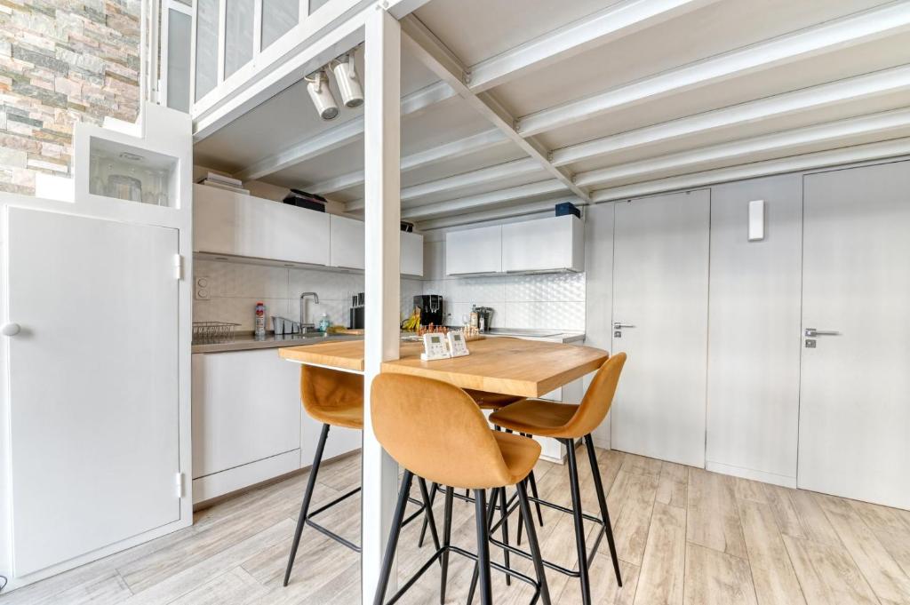 a kitchen with white cabinets and a wooden table and chairs at GuestReady - Stonewall Mezzanine in Brotteaux in Lyon