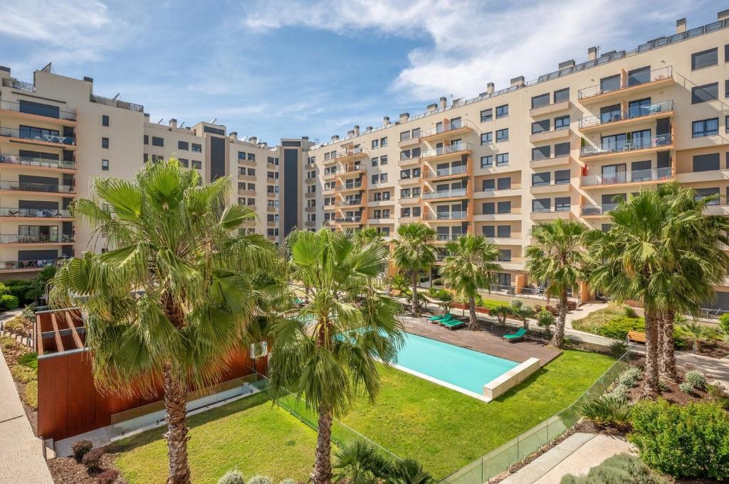un complexe d'appartements avec piscine et palmiers dans l'établissement GuestReady - Tranquil Seixal Haven, à Seixal