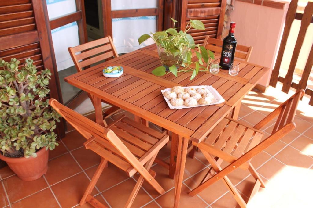 uma mesa de madeira com cadeiras e uma garrafa de vinho em La Perla nel Blu em Villasimius