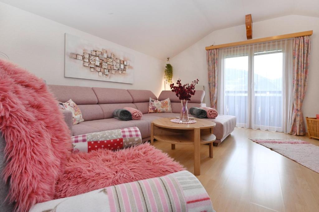 ein Wohnzimmer mit einem rosa Sofa und einem Tisch in der Unterkunft Appartement Sandra in Schruns-Tschagguns