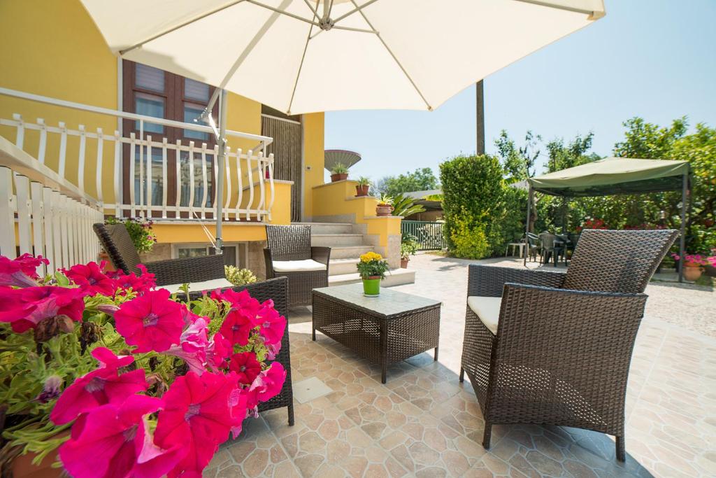 a patio with chairs and flowers and an umbrella at Il Melograno da Pina in Borgo Grappa