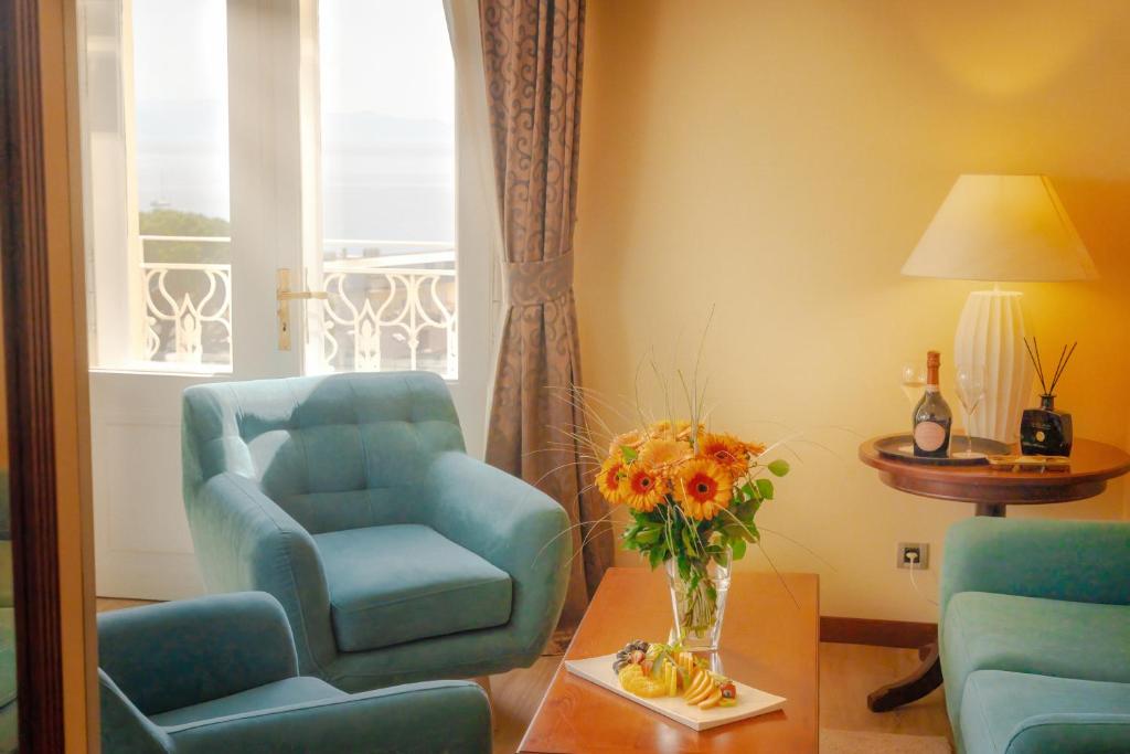 una sala de estar con una silla y un jarrón de flores en BRISTOL Hotel Opatija en Opatija