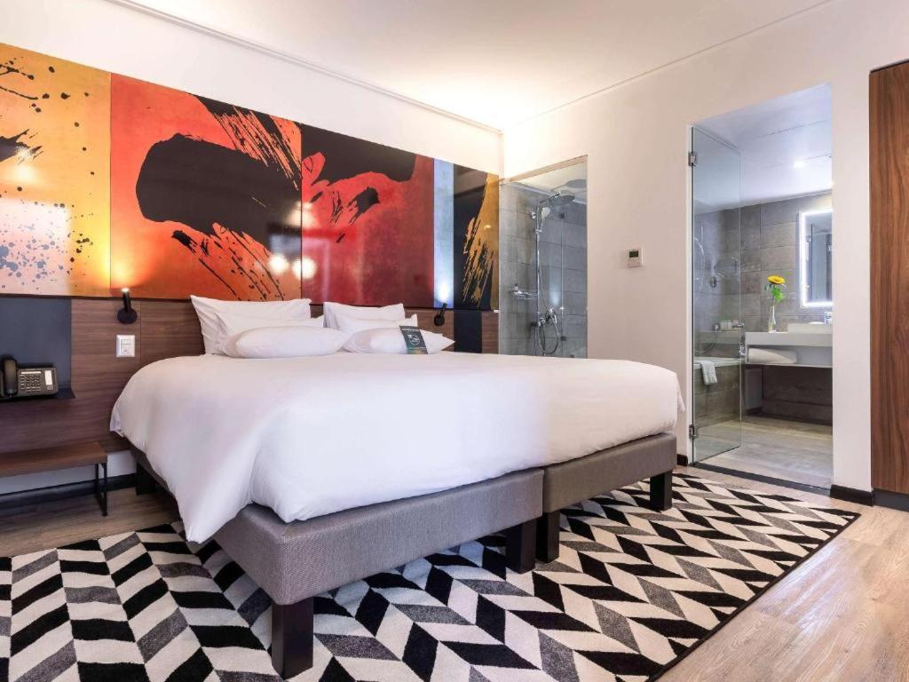 1 Schlafzimmer mit einem großen weißen Bett und einem Badezimmer in der Unterkunft Novotel Santiago Providencia in Santiago