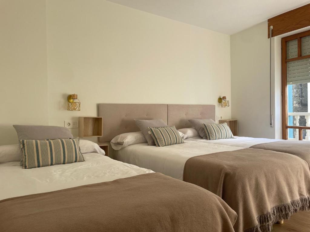 3 Betten in einem Zimmer mit weißen Wänden in der Unterkunft Pensión Cantabrico in Navia