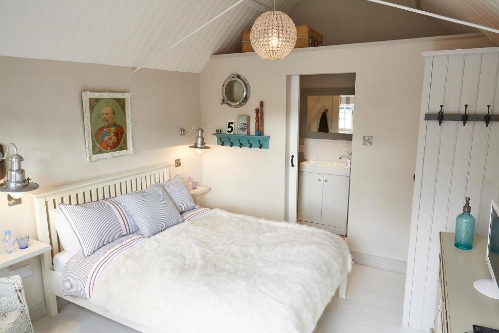 a bedroom with a white bed and a kitchen at The Sailor's House at Blue Door Barns in Beddingham