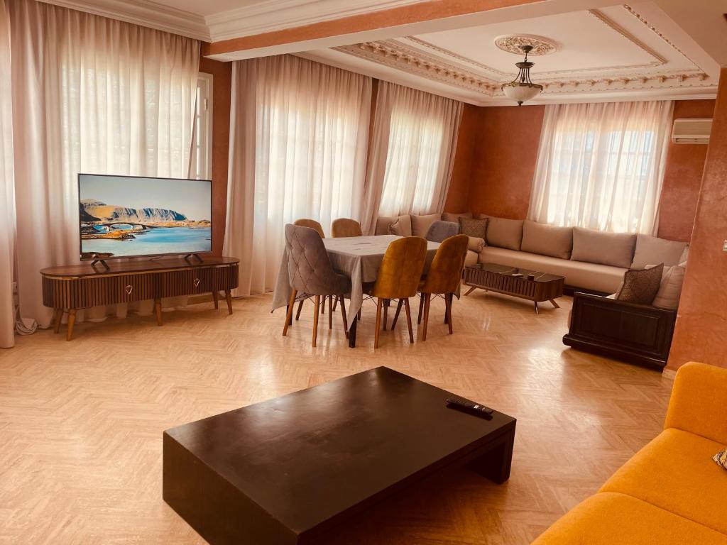 uma sala de estar com uma mesa e um sofá em Villa Dune Rouge de la Siesta em Mohammedia