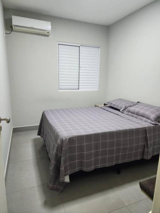 a bed in a white room with a window at Casa Temporada Terra Nova in Uberaba