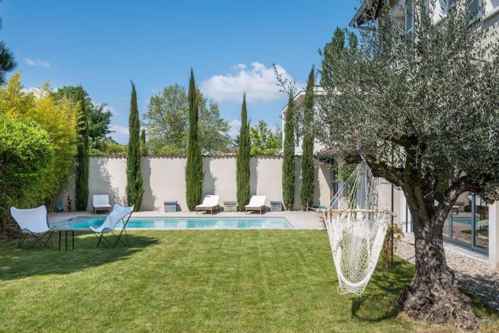 un cortile con piscina, sedie e albero di Les Cyprès - Amazing house with garden and pool a Tassin-la-Demi-Lune