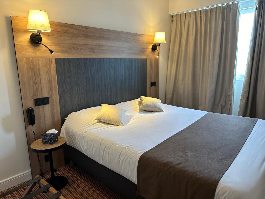 a hotel room with a large bed in a room at The Originals City, Hôtel Napoléon, La Roche-sur-Yon (Inter-Hotel) in La Roche-sur-Yon