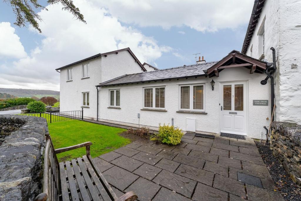 una casa bianca con una panchina davanti di Yew Tree Cottage a Bowland Bridge