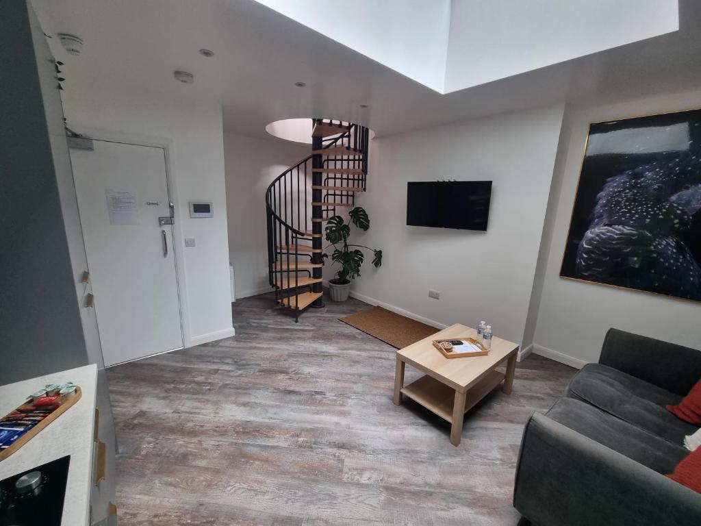 a living room with a couch and a spiral staircase at New city centre apartment in Hull