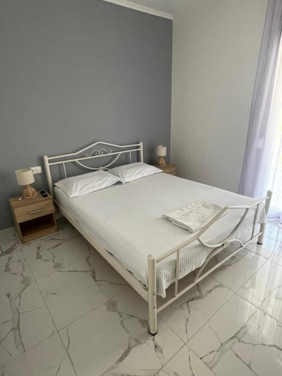 a white bed in a bedroom with a tiled floor at Antonis apartment in Paralia Dionysiou