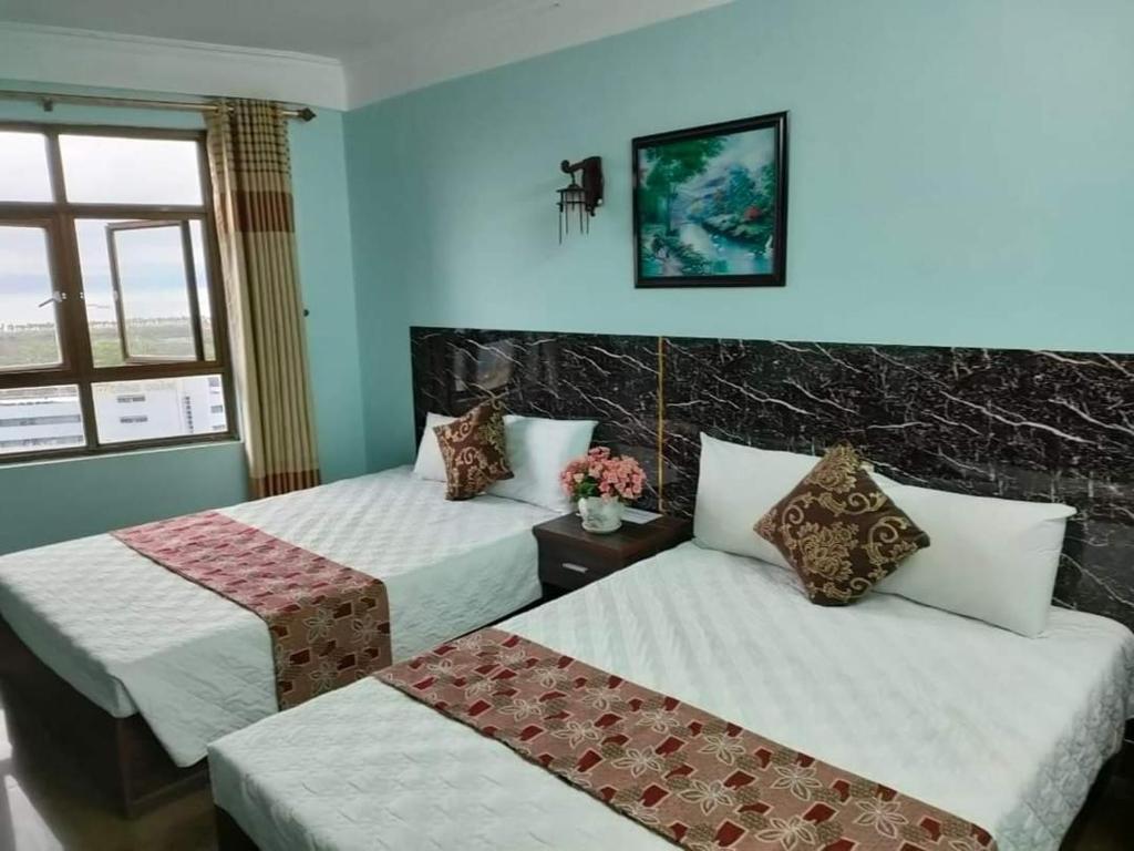 a hotel room with two beds and a window at Hien Thuc Hotel in Ninh Binh