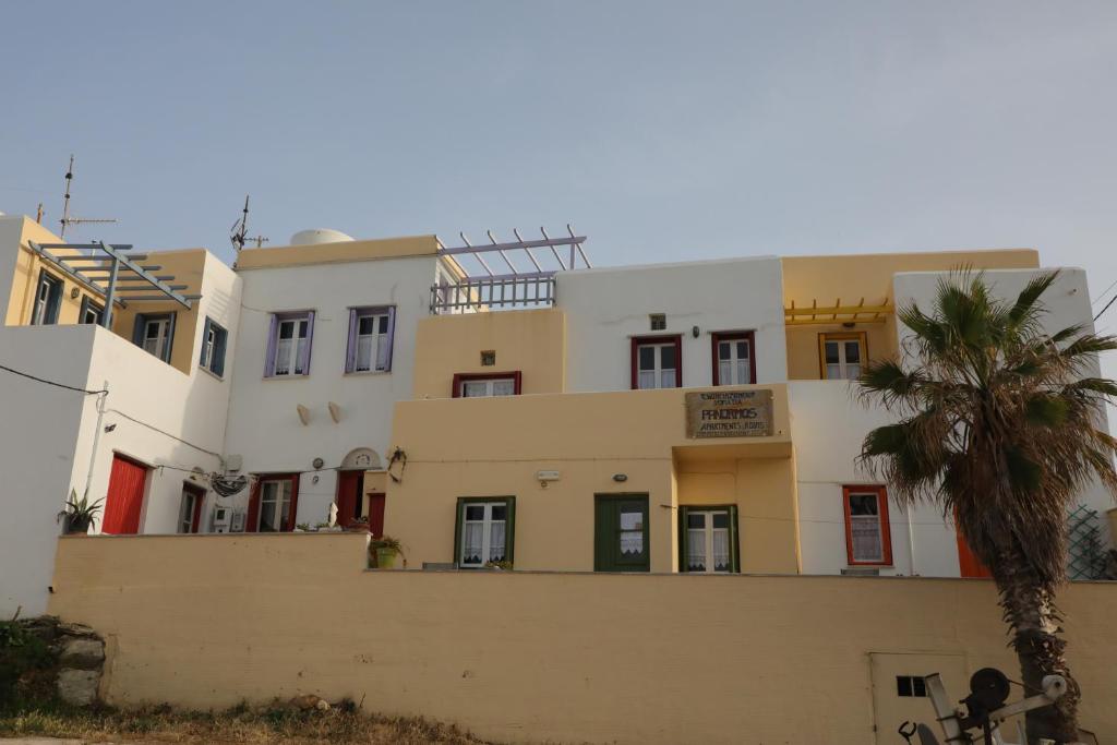 a building with a palm tree in front of it at Panormos Apartments in Panormos