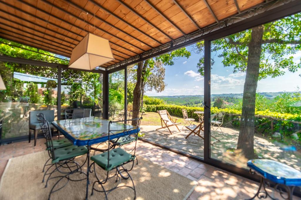 une véranda avec une table et des chaises en verre dans l'établissement Charming Country Retreat with stunning views, à Impruneta
