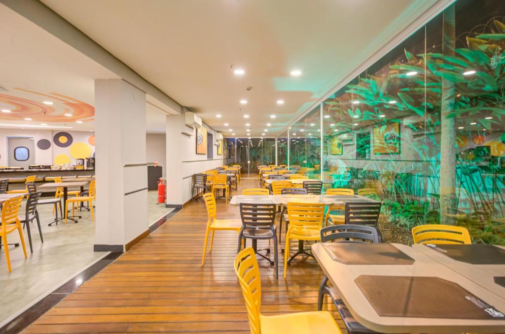 un restaurante con mesas y sillas y un mural en Transamerica Fit Villa Lobos, en São Paulo