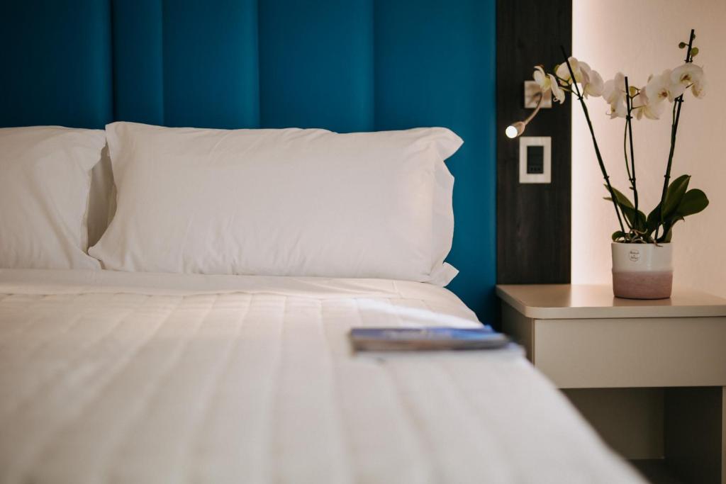 una cama blanca con control remoto encima en Dépendance Hotel Lalla, en Cesenatico