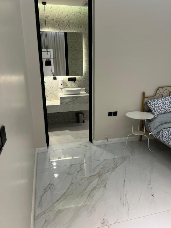 La salle de bains est pourvue d'un sol en marbre et d'un miroir. dans l'établissement شاليه ضي, à Haïl