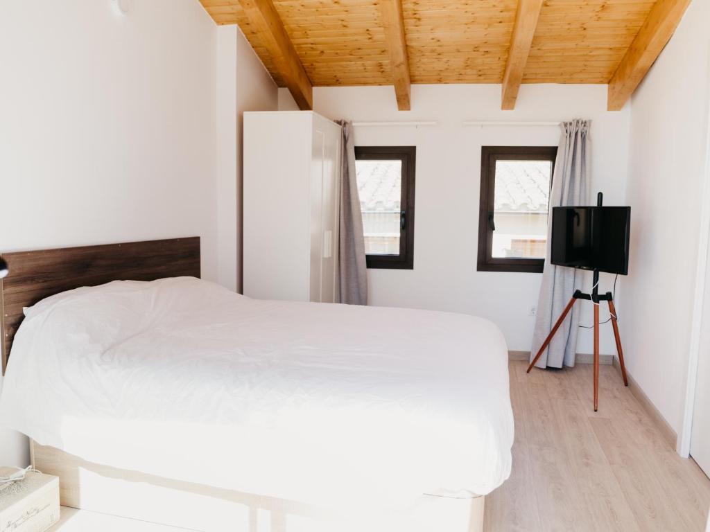 1 dormitorio con 1 cama blanca y TV en Camins del Priorat : Ermita Pinyeres en Masroig