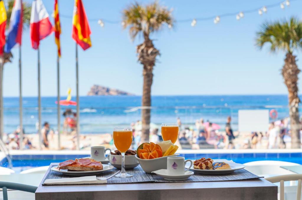 a table with food and drinks and the beach at Hotel Brisa in Benidorm
