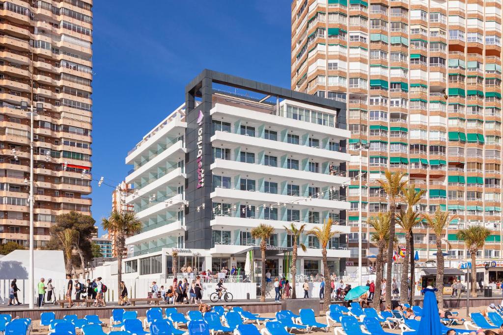 a large white building with blue beach chairs in front of it at Hotel Brisa in Benidorm