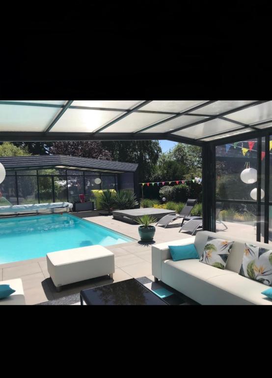 - une piscine avec un canapé blanc et des chaises à côté dans l'établissement La Villa Séquoia, à Les Bordes-Aumont