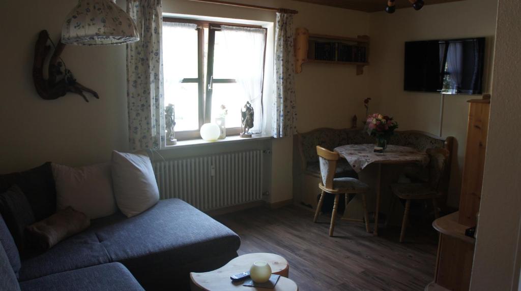 a living room with a couch and a table and a window at Ferienwohnung Auszeit in Fischen