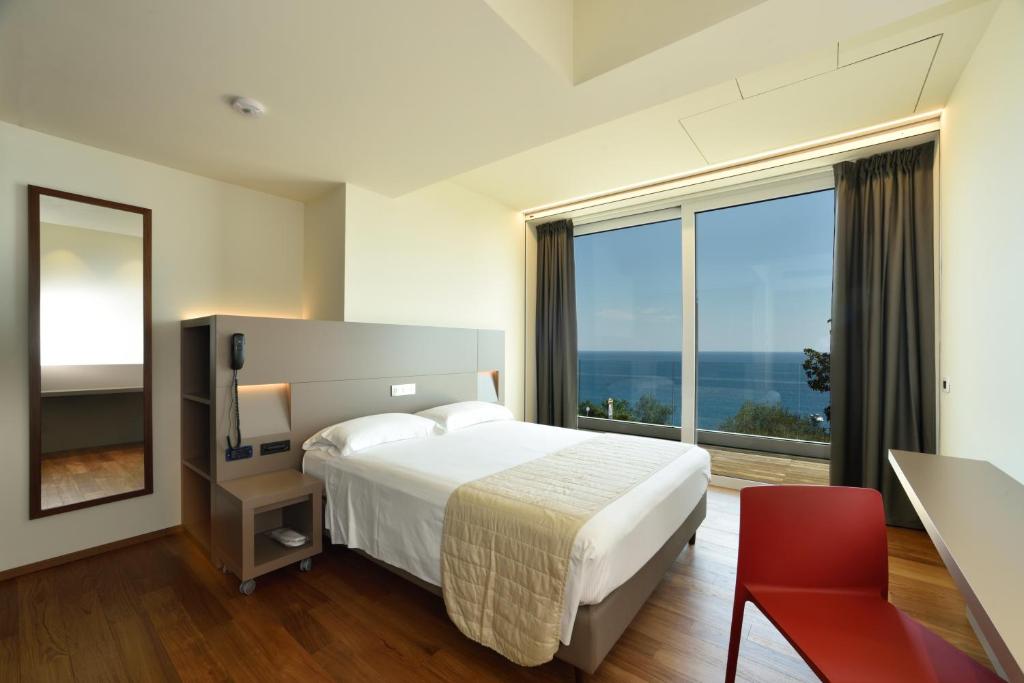 ein Hotelzimmer mit einem Bett und einem großen Fenster in der Unterkunft Hotel Le Roi in Varraze
