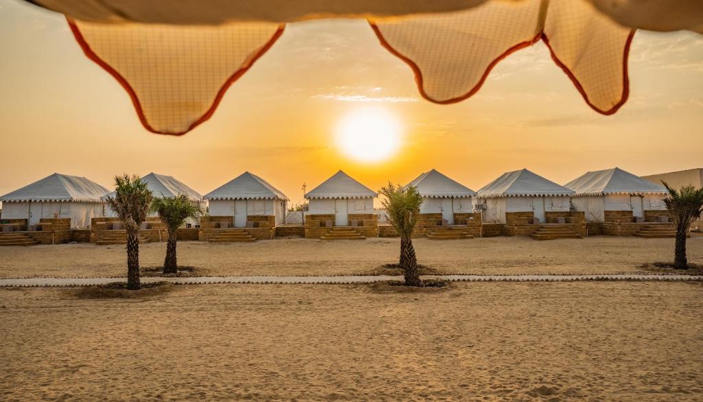 ジャイサルメールにあるDesert Heritage Luxury Camp And Resortのテントとヤシの木があるビーチの景色を望めます。