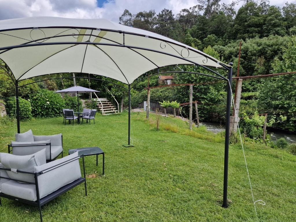 een grote paraplu in een tuin met stoelen en een tafel bij Dream corner by waterfalls, 20 min to Oporto in Parada