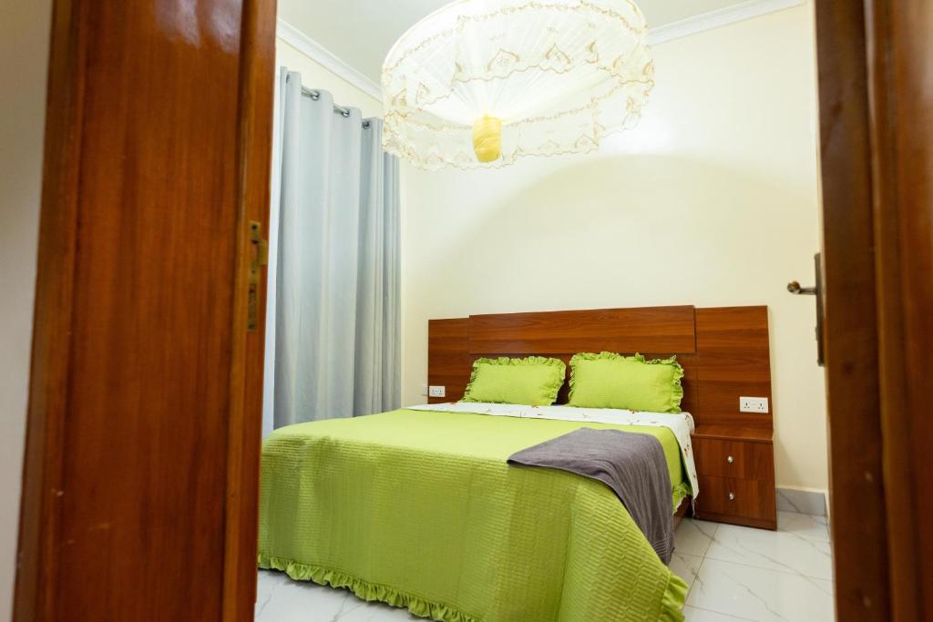 una camera da letto con un letto con lenzuola verdi e un lampadario a braccio di Venus VIP VILLA SUITES a Kigali