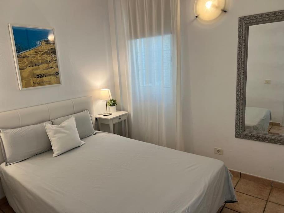une chambre avec un lit blanc et un miroir dans l'établissement Casa Macken con piscina climatizada y jacuzzi, à San Bartolomé