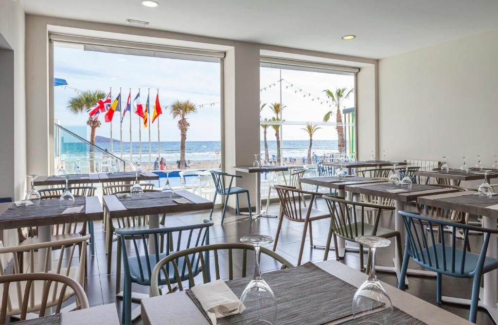 a restaurant with tables and chairs with a view of the beach at Hotel Brisa in Benidorm