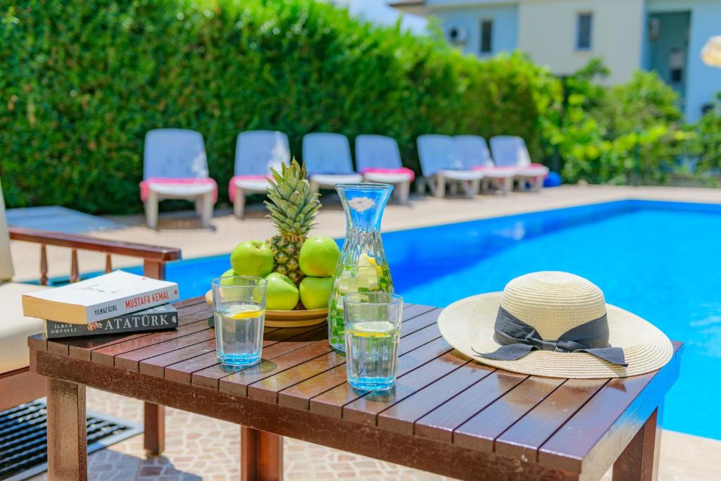 ein Tisch mit Hut und Brille neben einem Pool in der Unterkunft Kavak Garden in Fethiye