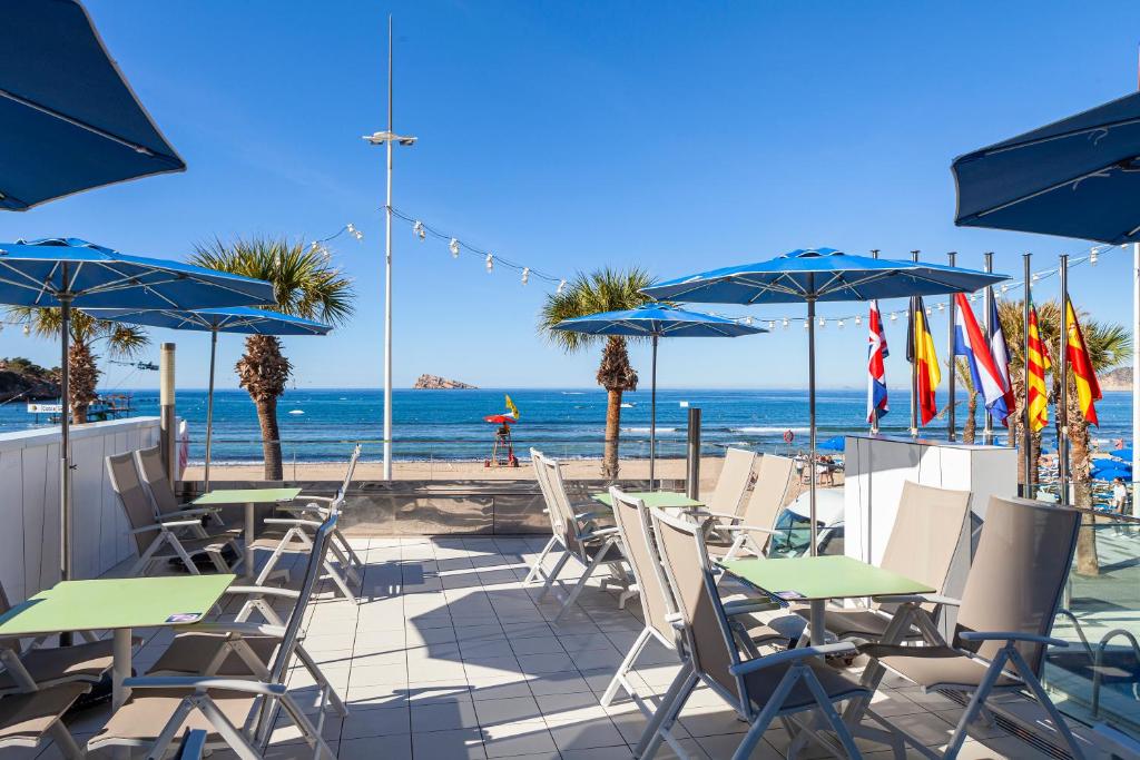 a patio with chairs and umbrellas and the beach at Hotel Brisa in Benidorm