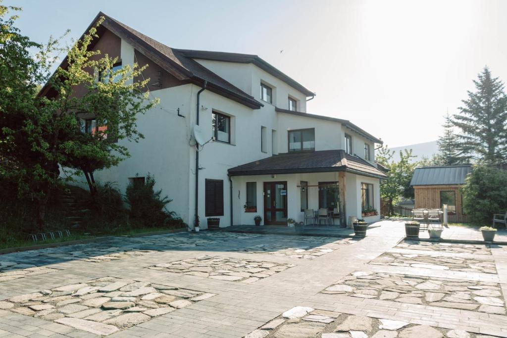 a large white house with a stone driveway at Penzion u Hanky in Telgárt