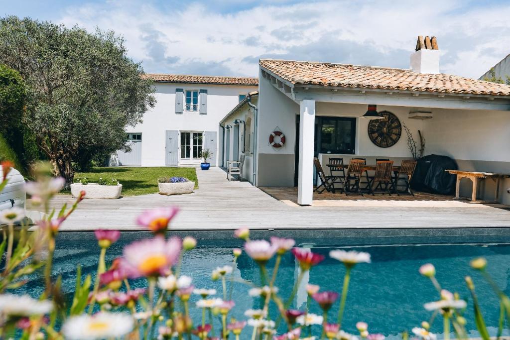 een huis met een zwembad en bloemen op de voorgrond bij Villa Cote Ouest in La Flotte