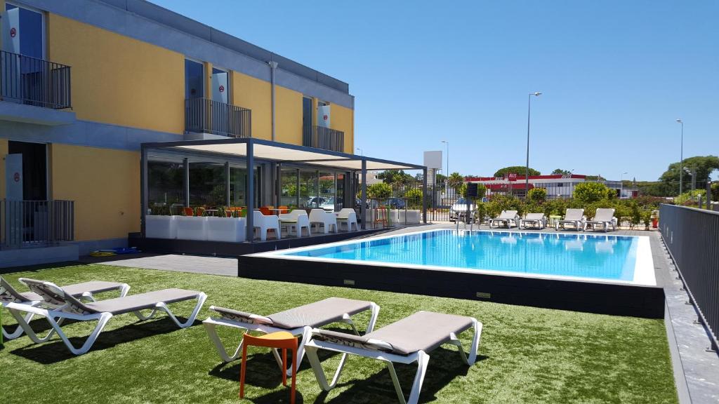 einen Pool mit Liegestühlen neben einem Gebäude in der Unterkunft Hotel 3K Faro Aeroporto in Faro