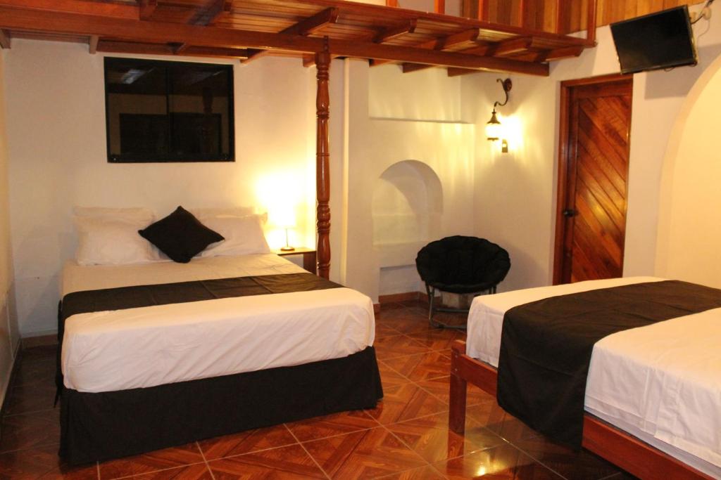 a hotel room with two beds and a chair at Epoca Iquitos in Iquitos