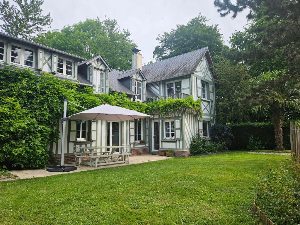 une maison blanche avec un parasol dans la cour dans l'établissement Authentique Maison Normande avec Piscine, à Tourgéville