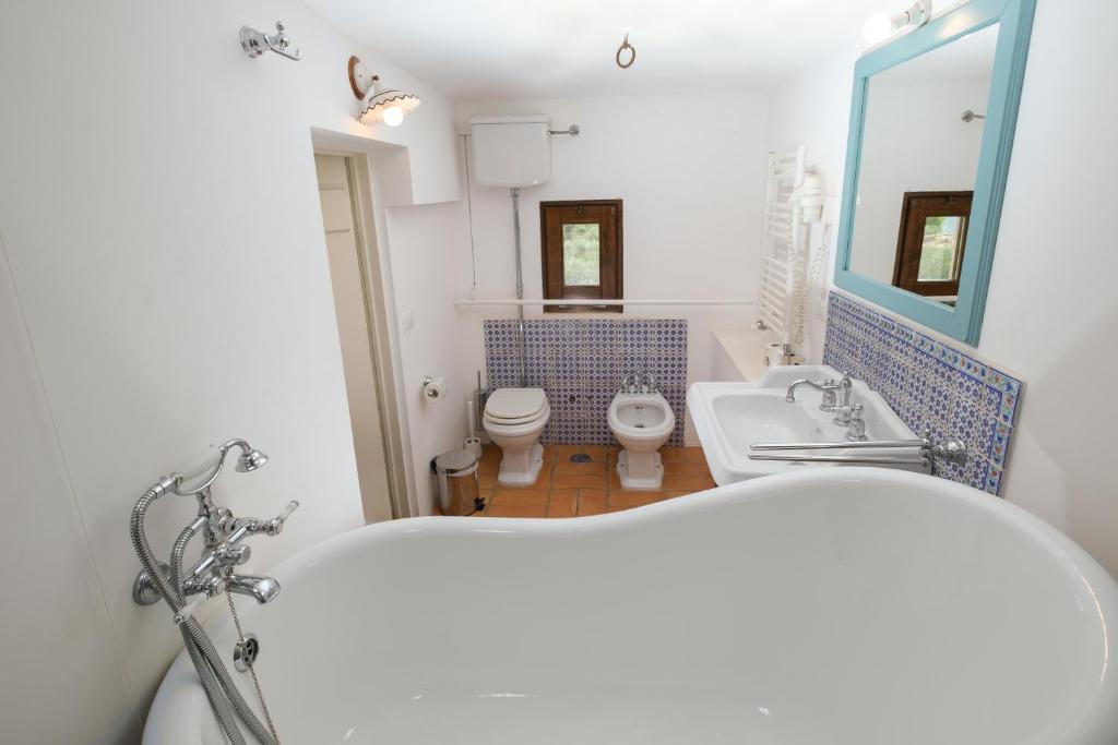 a bathroom with a tub and a toilet and a sink at Masseria Borgo Santuri in Ostuni