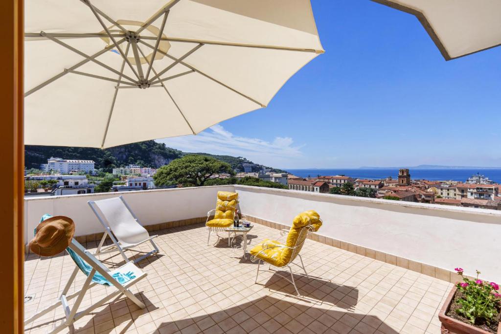 a group of chairs and an umbrella on a balcony at Ester's home Sorrento in Sorrento
