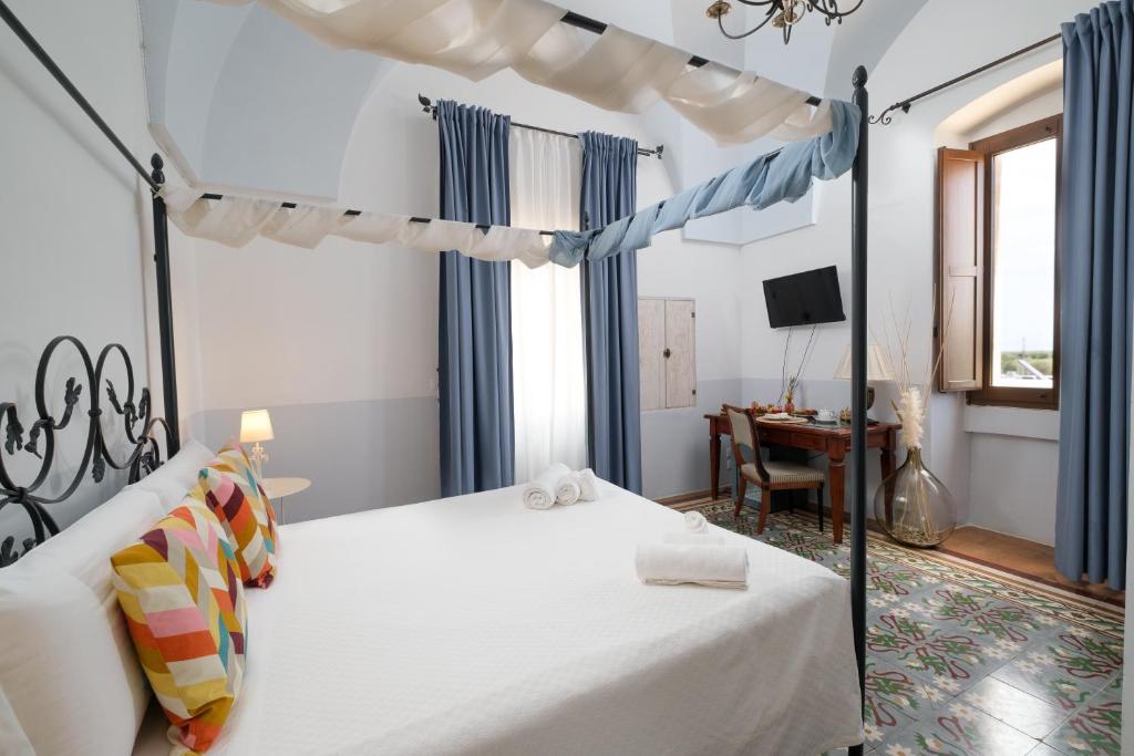 a bedroom with a canopy bed and a desk at Masseria Borgo Santuri in Ostuni