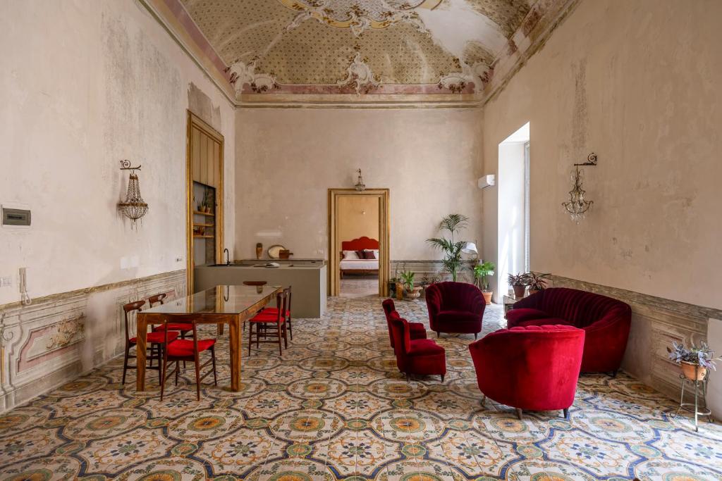 a living room with a table and red chairs at Palazzo Sant'Isidoro by DomuSicily in Palermo