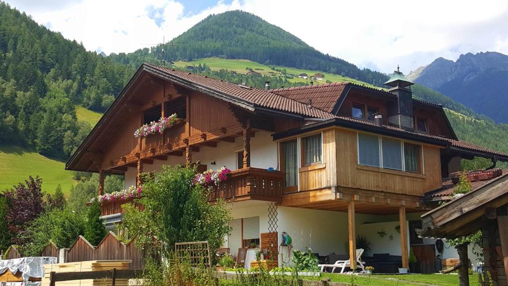 a house on a hill with mountains in the background at Appartement Wasserer in San Giovanni in Val Aurina