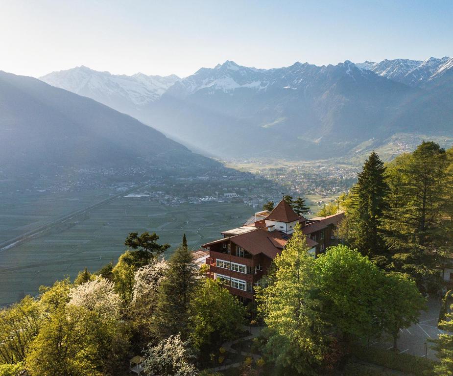 a house on a hill with mountains in the background at Relais & Chateaux Hotel Castel Fragsburg in Merano