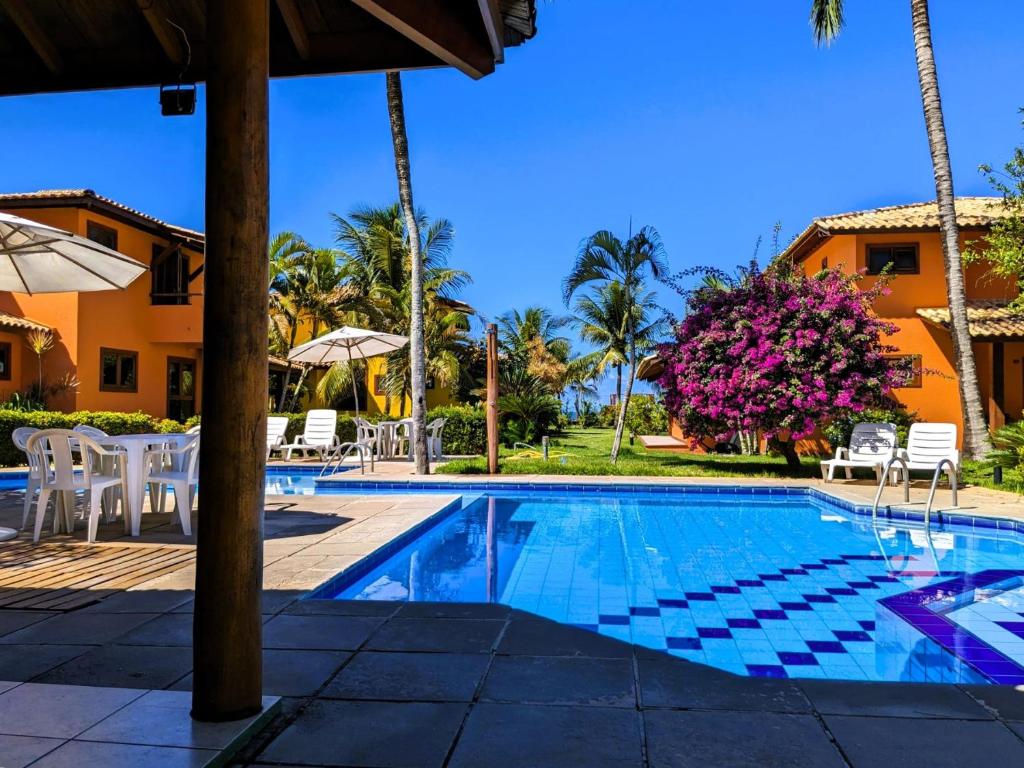 einen Pool in einem Resort mit Stühlen und Bäumen in der Unterkunft Residence Maria Vittoria Praia Arraial in Arraial d'Ajuda