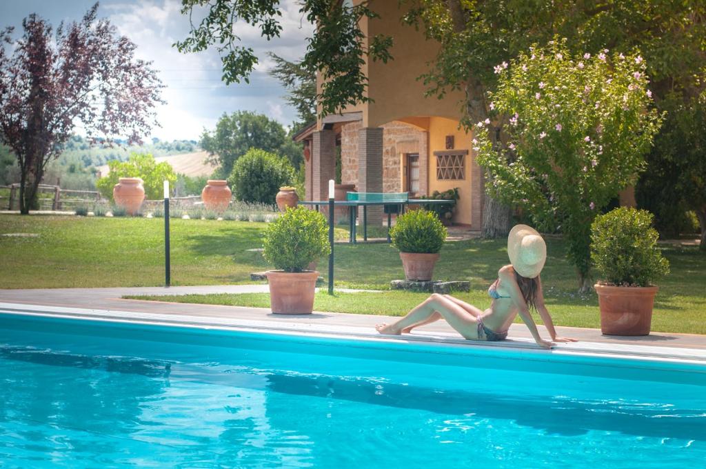 a woman sitting next to a swimming pool at Agriturismo Locanda Pantanello in Pitigliano