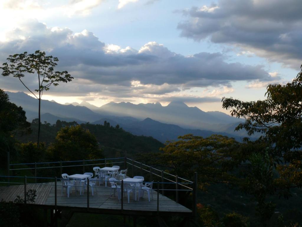 uma varanda com mesas brancas e cadeiras nas montanhas em La Esperanza Lodge and Reserve em Jardín